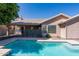 Backyard pool with blue tiles surrounded by concrete and mesh fencing with a tan home and green tree in the background at 5185 W Del Rio St, Chandler, AZ 85226