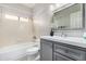 Traditional bathroom featuring a tub shower, window, grey vanity, and decorative mirror at 563 N Spanish Springs Dr, Chandler, AZ 85226
