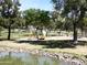 Community park featuring a playground, mature trees, a pond, and green space at 563 N Spanish Springs Dr, Chandler, AZ 85226