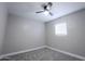 A simple bedroom featuring neutral gray walls, carpet, a window, and a ceiling fan with light at 6130 N 27Th Ave, Phoenix, AZ 85017