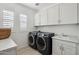 Bright laundry room features a sink, white cabinets, dark washer, dryer, and wood tile flooring at 634 E Deer Creek Rd, Phoenix, AZ 85048