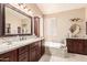 Bathroom featuring dual sinks, granite countertop, soaking tub, and stylish fixtures at 7103 E Medina Ave, Mesa, AZ 85209