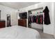 Bedroom with open closet with hanging clothes and a TV on top of wooden dresser at 7506 N 47Th Dr, Glendale, AZ 85301