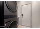 Modern laundry room with a stacked washer and dryer and a door to the outside at 7940 W Taro Ln, Glendale, AZ 85308