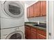 A laundry room with stacked washer and dryer and built in storage above a utility sink at 9012 S 47Th Pl, Phoenix, AZ 85044