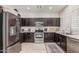 Modern kitchen features stainless steel appliances, granite countertops, and ample dark wood cabinet space at 9463 W Ross Ave, Peoria, AZ 85382