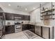 Well-equipped kitchen with stainless appliances, granite counters, dark wood cabinets, and stylish decorative shelving at 9463 W Ross Ave, Peoria, AZ 85382