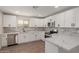 Well-lit kitchen boasts white cabinets, stainless steel appliances, marble backsplash, and quartz countertops at 119 E Hampton Ave, Mesa, AZ 85210