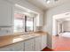 Bright kitchen with white cabinets, a double sink under a large window, and red tile floors at 1305 Coyote Pass Pass, Carefree, AZ 85377