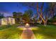 Inviting backyard featuring a fire pit surrounded by Adirondack chairs, complemented by pathway lighting and a large shade tree at 141 E Bonita Way, Tempe, AZ 85281