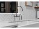 Close-up of white farmhouse kitchen sink with elegant faucet and white herringbone backsplash at 141 E Bonita Way, Tempe, AZ 85281