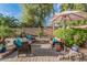 Landscaped backyard patio with cozy seating under an umbrella and lush greenery at 14294 W Edgemont Ave, Goodyear, AZ 85395