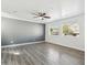 Bright living room with gray accent wall, hardwood floors, ceiling fan, and natural light from two windows at 1466 E Avenida Fresca --, Casa Grande, AZ 85122