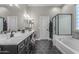 Stylish bathroom features dual sinks, black hexagon tile flooring, a shower, and a soaking tub at 18437 E Celtic Manor Dr, Queen Creek, AZ 85142