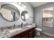 Bathroom featuring double sinks with granite countertops, modern fixtures, and a separate toilet at 18643 N 73Rd Ave, Glendale, AZ 85308