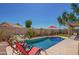 Backyard pool is framed by lush landscaping, rock features, lounge chairs, and a shade umbrella at 18643 N 73Rd Ave, Glendale, AZ 85308