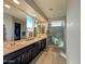 A dual sink bathroom vanity featuring tile flooring, a large mirror, a clear glass shower, and natural light at 22026 N 28Th Pl, Phoenix, AZ 85050