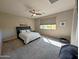 A carpeted main bedroom features a ceiling fan, neutral walls, and a large window providing natural light at 22026 N 28Th Pl, Phoenix, AZ 85050