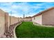 Landscaped backyard with green lawn, decorative rock border, and a view of surrounding trees at 2233 S Nielson St, Gilbert, AZ 85295