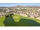 Aerial view of desert community with golf course and mountains, including single-Gathering homes with solar panels on their roofs at 22940 W Desert Bloom St, Buckeye, AZ 85326