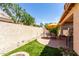 Backyard featuring artificial grass, brick patio, dining set, fire pit, and privacy wall at 22940 W Desert Bloom St, Buckeye, AZ 85326
