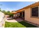Landscaped backyard featuring a covered patio, brick, artificial turf and a dining set at 22940 W Desert Bloom St, Buckeye, AZ 85326