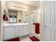 Bright bathroom with white vanity, large mirror, and glass-enclosed shower with red accents at 22940 W Desert Bloom St, Buckeye, AZ 85326
