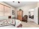 Well-lit bedroom with a quilt-covered bed, window blinds, and a traditional accent chair at 22940 W Desert Bloom St, Buckeye, AZ 85326