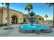 Stunning clubhouse entrance with water fountain feature, desert landscaping, stucco architecture, and beautiful palm trees at 22940 W Desert Bloom St, Buckeye, AZ 85326