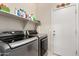 Laundry room featuring a modern washer and dryer, along with storage and a convenient exterior door at 22940 W Desert Bloom St, Buckeye, AZ 85326