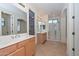 Bright bathroom with double vanity, neutral tile floors, glass-enclosed shower, and a walk-in closet at 248 S 167Th Dr, Goodyear, AZ 85338