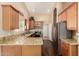 Bright kitchen featuring granite counters, stainless fridge, wood cabinets, and hardwood floors at 2753 E Kenwood St, Mesa, AZ 85213