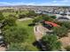 An aerial view of the park showcasing lush greenery, a playground, and residences with mountain views at 37084 W Prado St, Maricopa, AZ 85138
