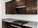 Close-up of kitchen features including granite countertops, stainless steel appliances, and dark wood cabinetry at 37084 W Prado St, Maricopa, AZ 85138