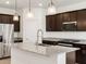 Stylish kitchen with island, stainless steel appliances, granite countertops, dark cabinets, and pendant lights at 37084 W Prado St, Maricopa, AZ 85138