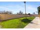 Large backyard featuring a well-maintained lawn, tall privacy fence, and walkway along the house at 4007 W Thunderbird Rd, Phoenix, AZ 85053