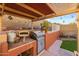 Outdoor kitchen under a pergola, complete with a grill, pizza oven, and countertop space for entertaining at 4715 E Carmen St, Phoenix, AZ 85044