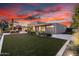 Expansive backyard with artificial lawn, modern home exterior, and vibrant sunset sky at 4835 E Onyx Ave, Paradise Valley, AZ 85253