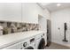 Modern laundry room featuring sleek cabinetry, front load machines, and stylish backsplash at 4835 E Onyx Ave, Paradise Valley, AZ 85253