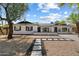 Charming single-story home featuring a white brick facade and well-manicured front yard with desert landscaping at 6271 E Evans Dr, Scottsdale, AZ 85254