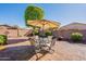 Open backyard with patio seating under an umbrella and a mature tree at 6397 S Pinaleno Pl, Chandler, AZ 85249