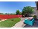 Private backyard with colorful accent wall, well manicured lawn and mature tree at 7159 S Dodane Ct, Gilbert, AZ 85298