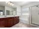 Bright bathroom featuring double vanity, glass shower, and soaking tub with a neutral color palette at 7159 S Dodane Ct, Gilbert, AZ 85298