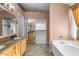 Bright bathroom with double sink vanity, granite counters, soaking tub, and walk-in closet at 7778 N 51St Ln, Glendale, AZ 85301