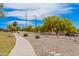 Community walking path featuring gravel landscaping, trees, blue sky, and overhead power lines at 9309 E Obispo Ave, Mesa, AZ 85212