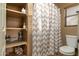 Functional bathroom featuring a shower with a striped curtain and a convenient storage shelf at 9548 E Kiva Ln, Gold Canyon, AZ 85118