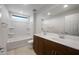 Bright bathroom featuring double sinks, modern fixtures, and tub with shower at 17782 W Getty Dr, Goodyear, AZ 85338