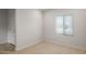 Bright bedroom with neutral carpet, white walls, a window with blinds, and a white door with chrome handle at 17782 W Getty Dr, Goodyear, AZ 85338