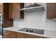 Modern kitchen features an electric cooktop, white subway tile backsplash, and stainless steel range hood at 17782 W Getty Dr, Goodyear, AZ 85338