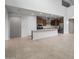 Open concept living space with light tile flooring, tall ceilings, and a view into the kitchen at 17782 W Getty Dr, Goodyear, AZ 85338